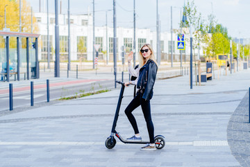 Young beautiful woman riding an electric scooter to work, modern girl, new generation, electric transport, ecology, ecological transport, sunset, electric skateboard