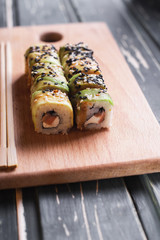 Sushi with salmon on a wooden board on a dark wooden background