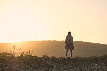 Young girl walking along a stone slope in the sunset rays on a background of hills. Tourism and outdoor concept.