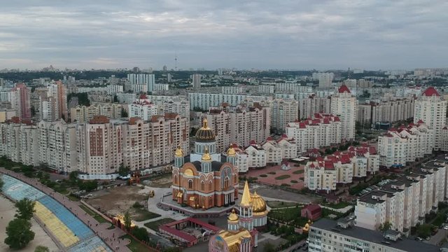 Aerial photography. Orthodox Christian Church on the Obolonskaya embankment in the spring in Kiev. Many houses built along the Dnieper Bay. Drone.
