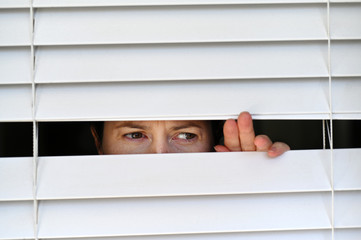 Suspicious person looking outside home window