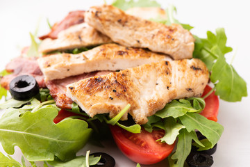 A chicken salad with rucola bacon and tomato
