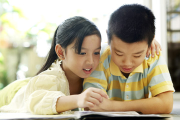 Brother and sister reading magazine together
