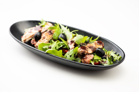 A chicken salad with rucola bacon and tomato