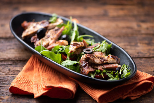 A chicken salad with rucola bacon and tomato