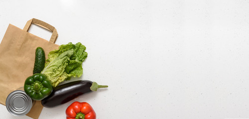 Vegetables, red and green peppers, eggplant, cucumber, canned food, lettuce lie on a paper bag on isolated background. Top view copy space. Donation. contactless food delivery.