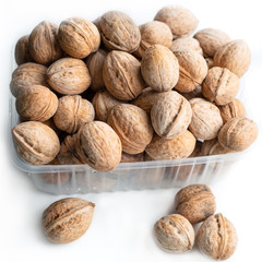 a bunch of walnuts lies in a container on a white background, tasty wholesome food,