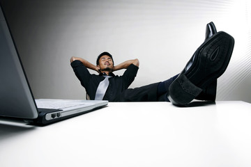 Businessman with hand behind his head and feet up on desk