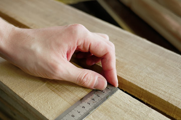 Construction and repair. Men's hands line measure the width of a wooden board. Hands with a close-up tool.