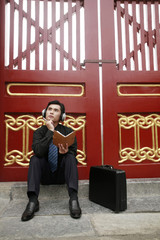 Businessman with headphones thinking while holding a book