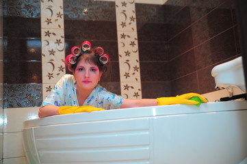 housewife in hair curlers washes the bathroom