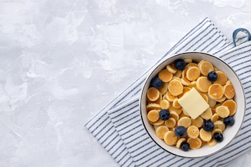 Tiny mini pancake cereal. Home made breakfast with blueberries, jam and juice on gray background