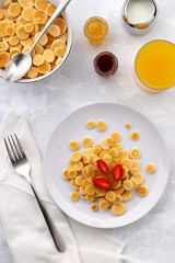 Tiny mini pancake cereal. Home made breakfast with raspberries, jam and juice on gray background