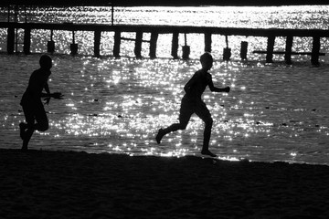 Czarno- białe zdjęcie. Sylwetka dziecięca. Radosny dzieci biegają na brzegu jeziora.