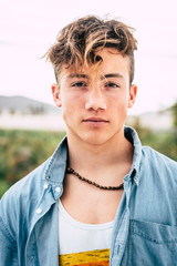close up and portrait of millennial boy or teenager seriously looking at the camera - handsome and...