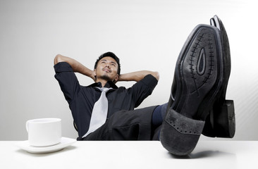 Businessman with hands behind his head and feet up on desk
