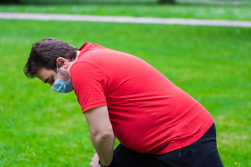 Fat man wearing face mask doing exercises after quarantine