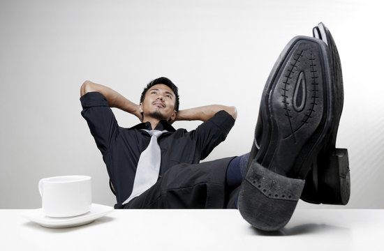 Businessman with hands behind his head and feet up on desk