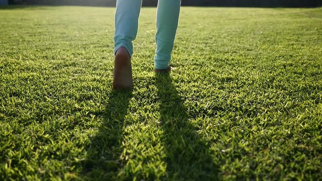 Feet of a young girl walking on a green grass in the morning Slow Motion 