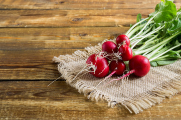 a bunch of ripe red radishes on a wooden background.