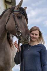 Fototapeta premium A girl next to a horse on a farm in the background of a sky.