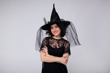 halloween concept - portrait of happy woman in black witch halloween costume and hat over white background with copy space