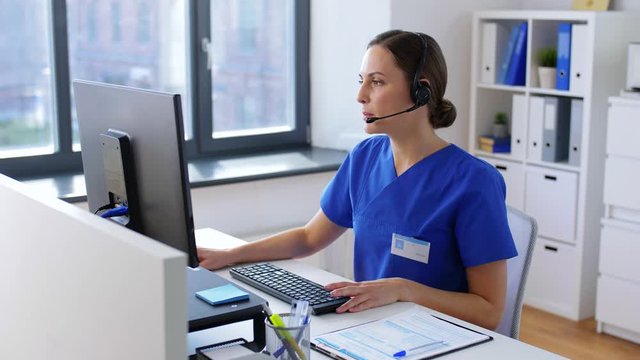 medicine, technology and healthcare concept - female doctor or nurse with headset and computer working at hospital