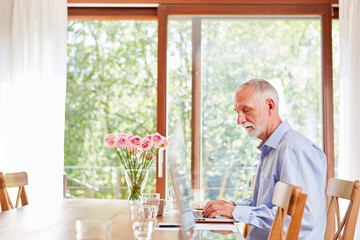 Senior man writes on the laptop computer