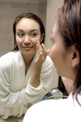 Woman in bathrobe looking at mirror