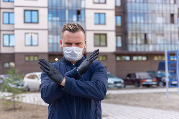 Kovid concept 19. portrait of a Caucasian man on the street showing a hand gesture puts on a protective mask and gloves, prevent the spread of the crown virus.keeping a safe distance.