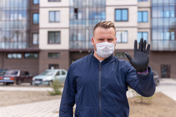 Kovid concept 19. portrait of a Caucasian man on the street showing a hand gesture puts on a protective mask and gloves, prevent the spread of the crown virus.keeping a safe distance.