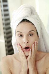 Woman with towel wrapped hair showing shock expression