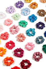 Cropped detailed shot of a set of colorful scrunchies made of velvet fabric. The bright hair...