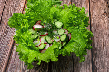 Green vegan salad made from green leaves mix, cucumbers and radishes