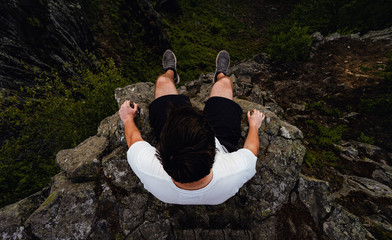 Man on the edge of a rock, looking at his feet. Aerial View Travel Lifestyle Adventure Vacation Concept - Powered by Adobe