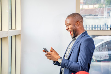 young black businessman feeling excited and happy while using his mobile phone