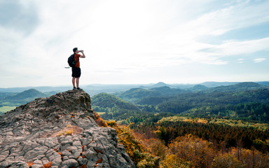 Outdoor young man with a water bottle at the edge of a cliff overlooking the mountains below....
