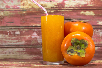 Fresh persimmon juice and fruits (Diospyros kaki L.) on reddish aged wooden background