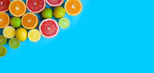 Blue background with different sliced citrus - oranges, grapefruits, lemons and limes. Flat layout with space for text. Banner