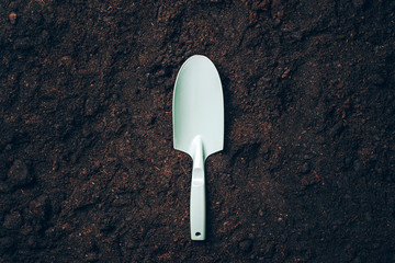 Small shovel with handel over soil background. Agriculture, organic gardening, planting or ecology concept.