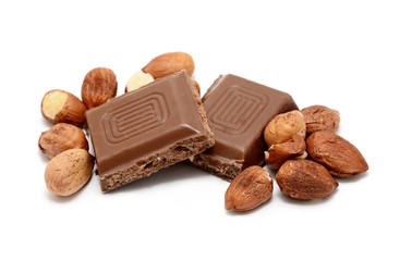 Chocolate squares with whole hazelnuts over white background.