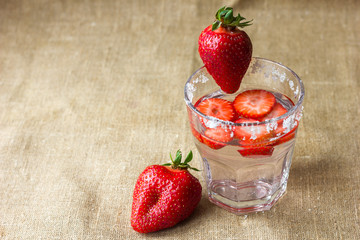 A refreshing drink of strawberries in a glass and berries on a background of a napkin made of...