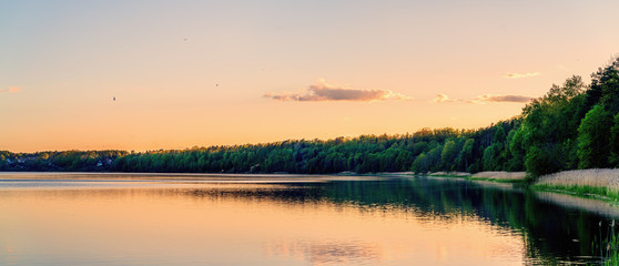 Panoramic view of lake coast on sunset in spring.