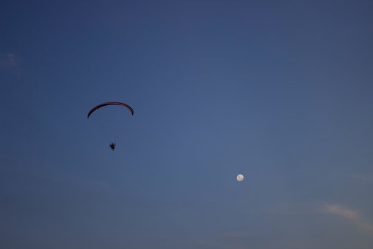 Low Angle View Of Person Paragliding In Sky At Dusk