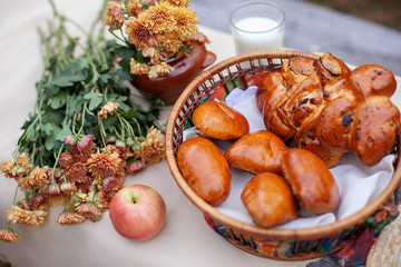 Outdoor summer picnic on old rustic table. Beautiful rustic picnic composition with with bread, a buns, apple and bouquet of flowers on wooden table in autumn park. Healthy food concept. no people
