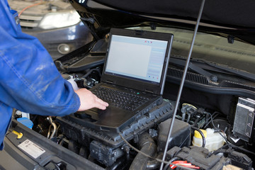 Professional mechanic diagnoses a car in a car service. Electrical diagnostics of a car.