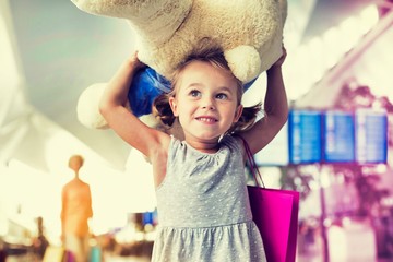 Portrait of young little girl holding her big teddy bear in airport
