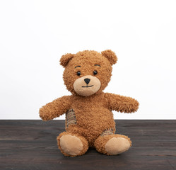 brown teddy bear sits on a brown wooden table