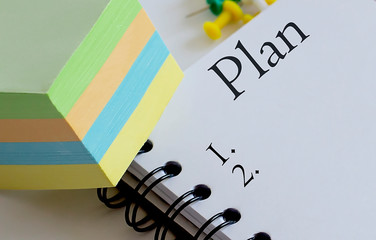 Plan .Desk with stationary and notebook with text and stickers.