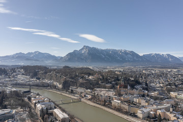 Aerial drone view of Salzburg snowy old town with view of Hohensalzburg fortress Unesberg mountain in winter morning
